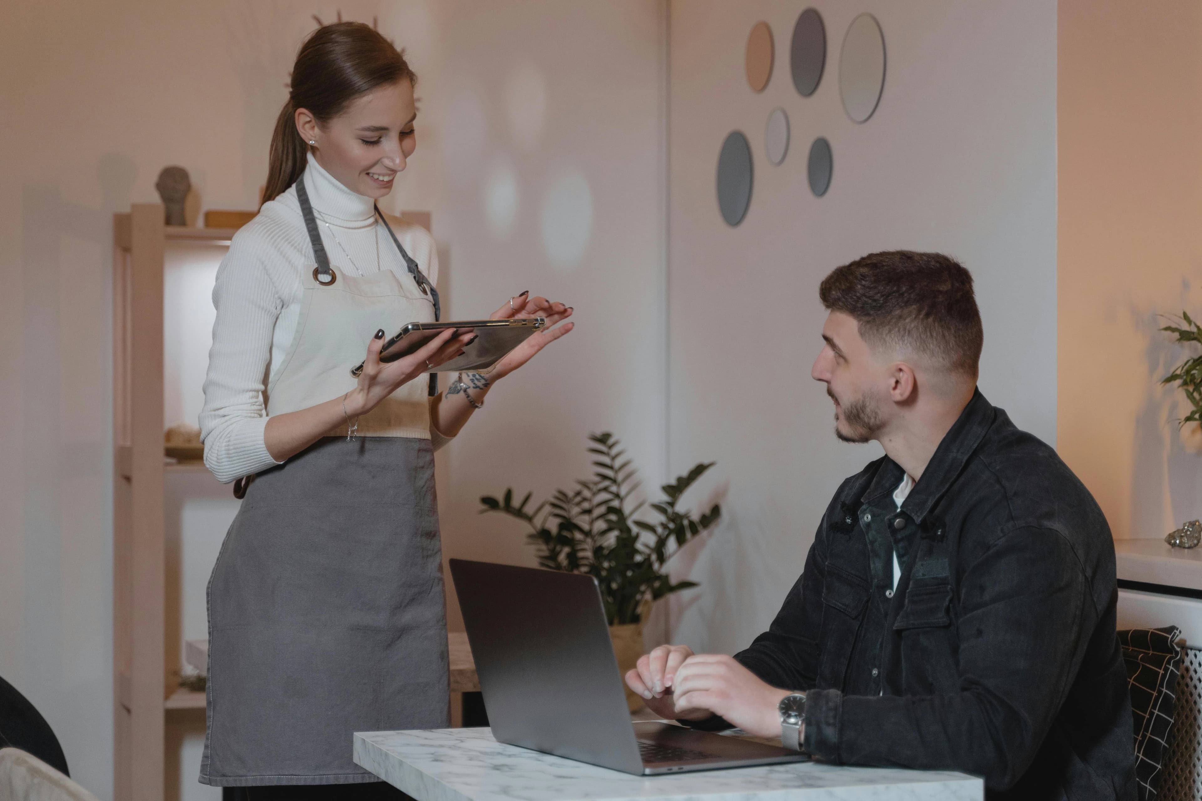 Server confirming details on a tablet while assisting a seated guest