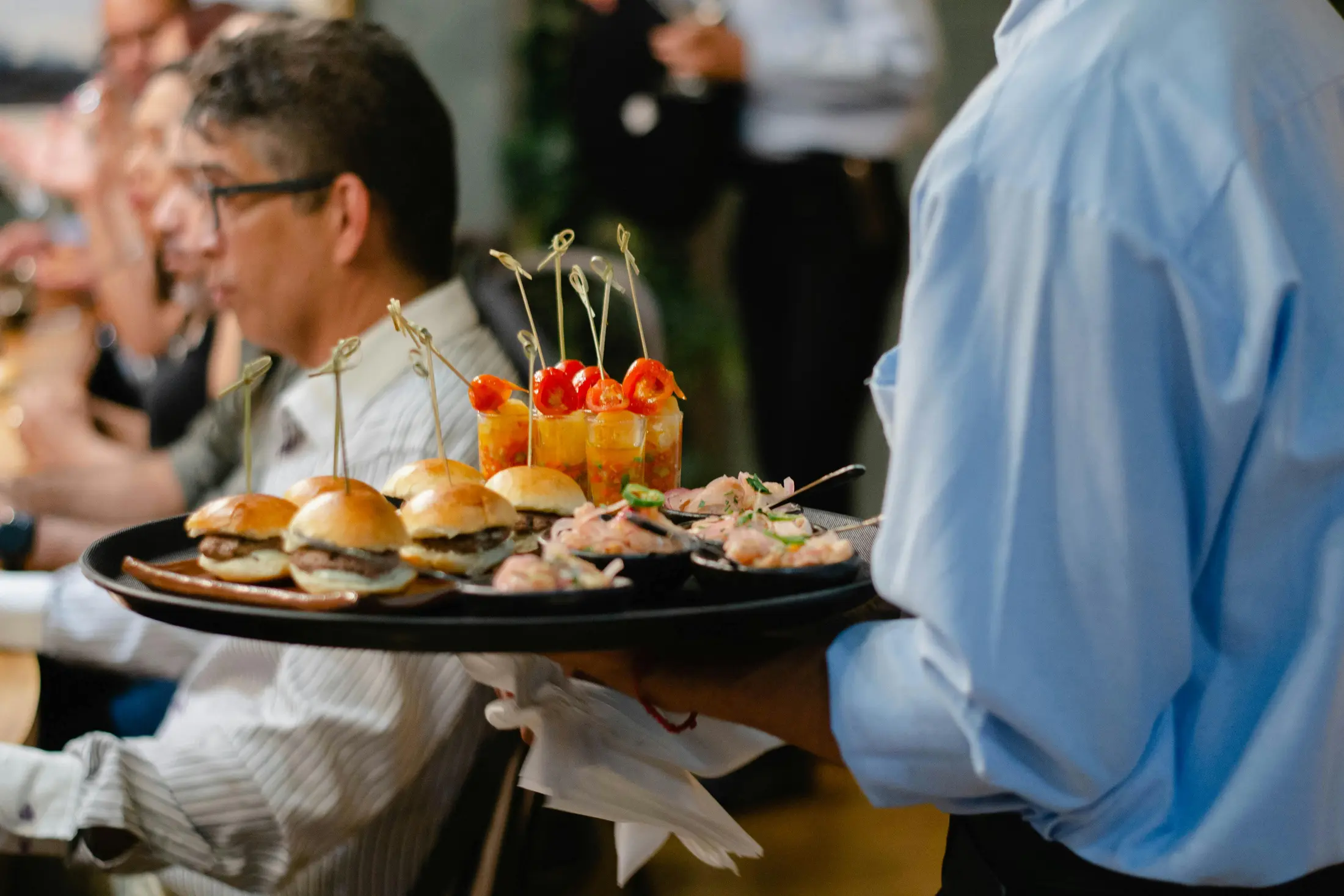 Server delivering food to guests in a busy restaurant dining room